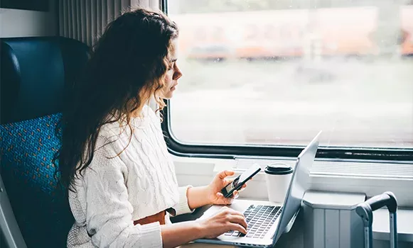 Businessfrau sitzt im Zug vor ihrem Laptop und arbeitet