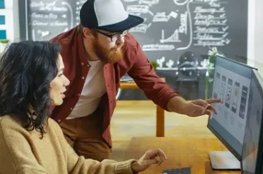 Ein Mann und eine Frau sitzen im Büro vor einem Bildschirm