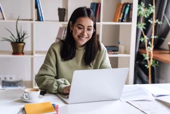 Junge Frau arbeitet am Laptop und lächelt